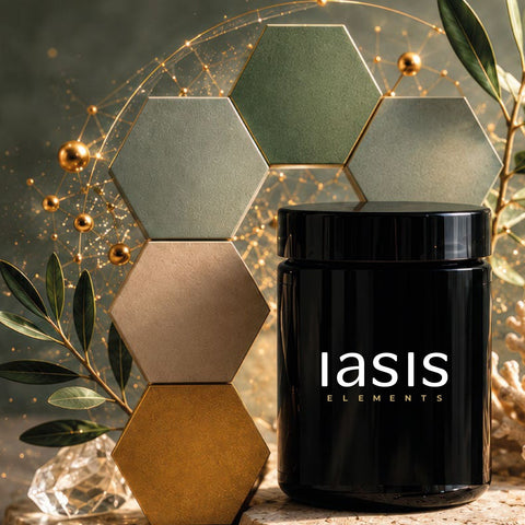 Ein schwarzes Glas mit der Aufschrift „iasis ELEMENTS“ vor einem Stapel sechseckiger Fliesen, die mit goldenen Kugeln und Grünpflanzen verziert sind.